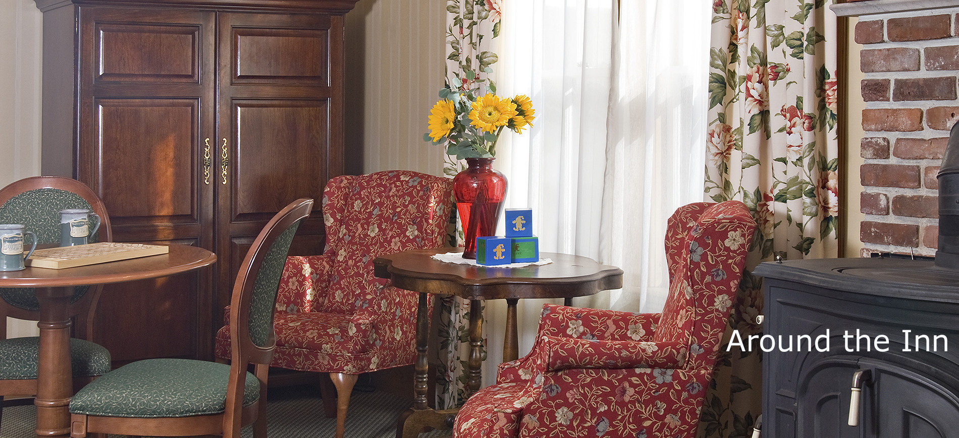 Inn at Ellis River sitting room with round table & chairs, two burgunday print wing chairs between table