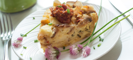 Chive and cheddar strata on white plate with chive blossom garnish