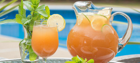 Iced tea pitcher and glass with pool in background