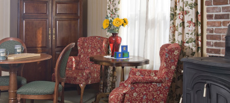 Two wing chairs next to round table with sunflowers in red vaser