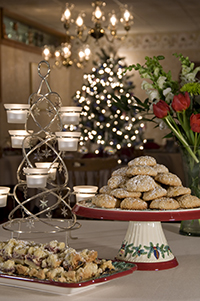 silver & white votive candle stand, tray of cookies, platter of cookies, vase of flowers & Christmas tree in background