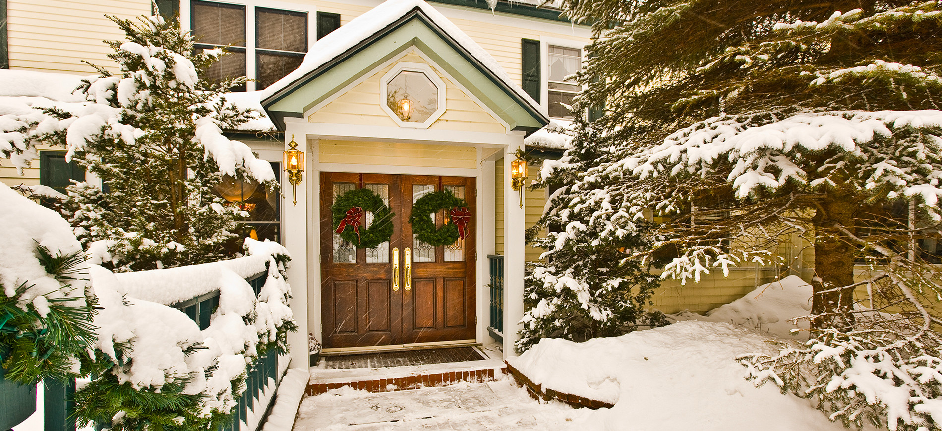 Inn at Ellis River portico & entry doors with wreaths in snow