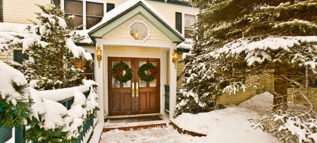 Inn at Ellis River portico & entry doors with wreaths in snow