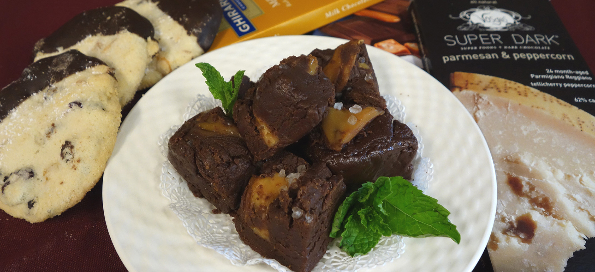 Chocolate fudge on white plate with chocolate dipped cookies on left