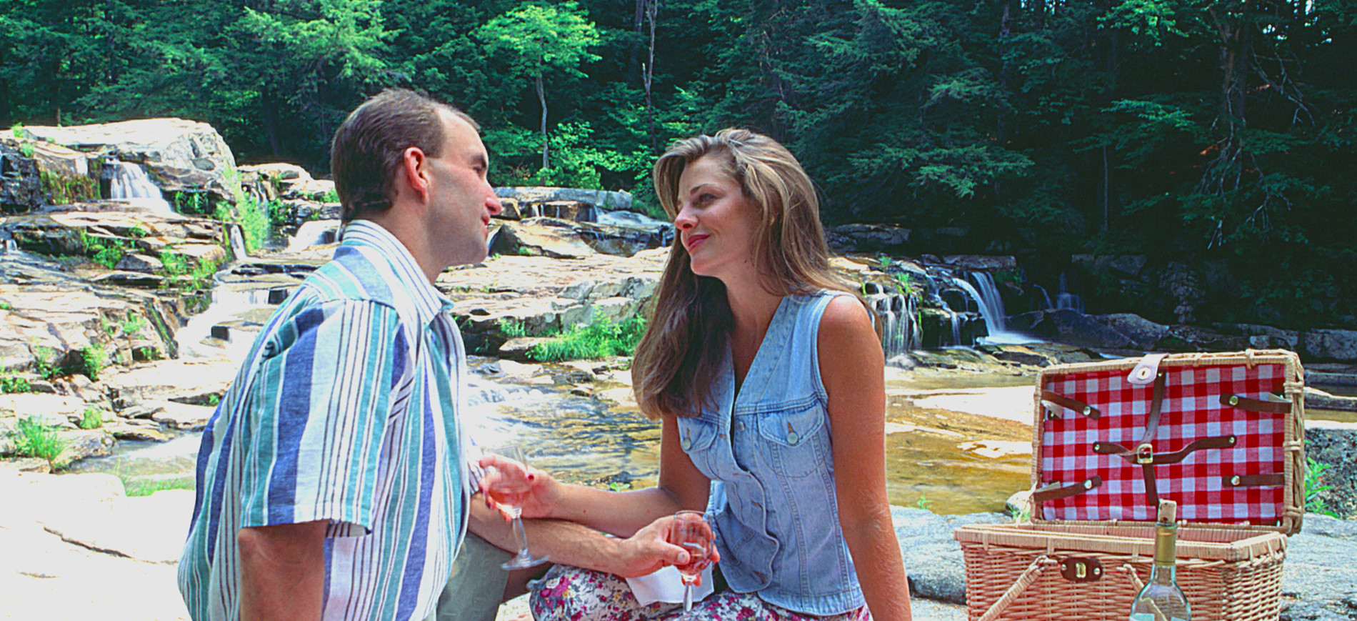 Couple toasting at picnic lunch by waterfall