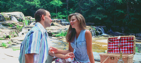 Couple toasting at picnic lunch by waterfall