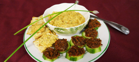 Sun dried tomato pesto on cucumber rounds, pesto dip in bowl and on crackers