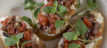 Three pieces of bruschetta topped with chopped tomato & oregano garnish