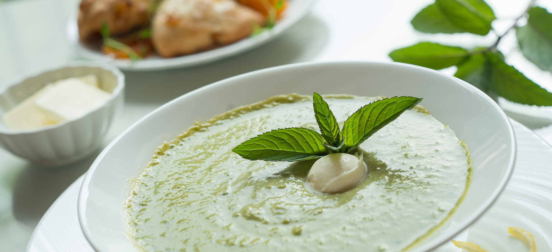 white bowl of pea soup garnished with mint