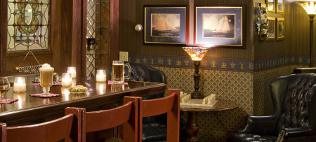 Bar with drinks & bar stools, chess set, lamp, pictures in background