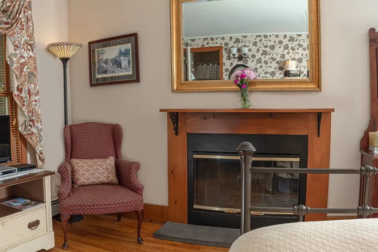 fireplace, gold-framed mirror, and burgundy chair.