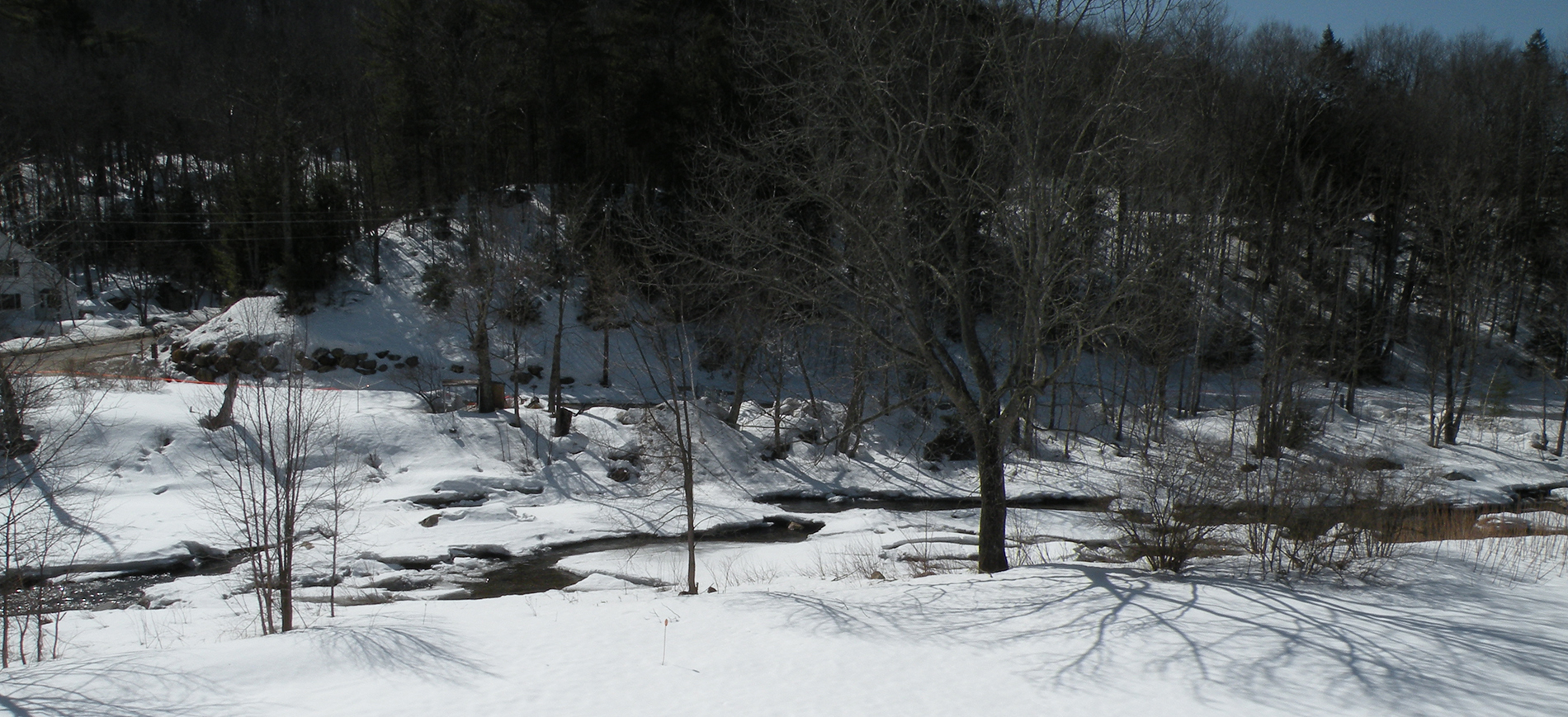 snow along tree lined Ellis River NH in winter.