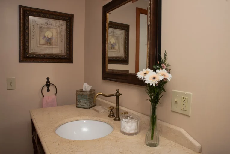 Bathroom with a sink, mirror, and white flowers.