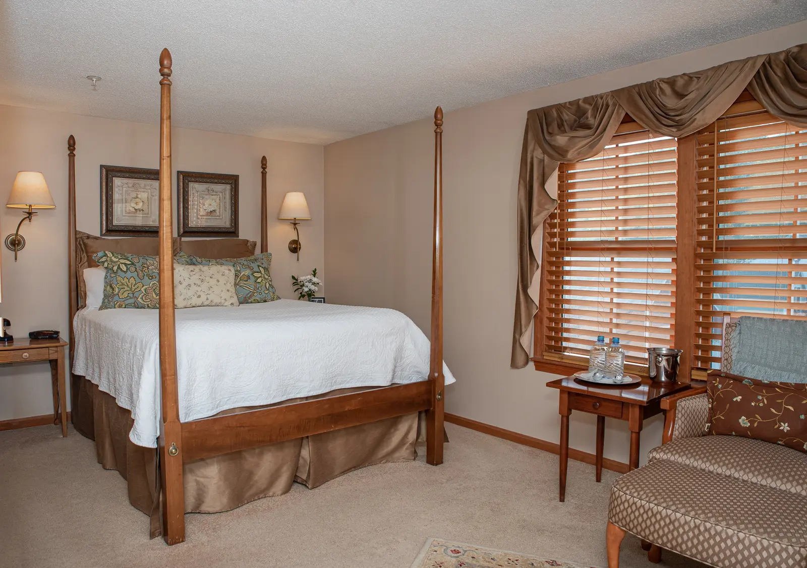 Bedroom with wooden four-poster bed and window seat.