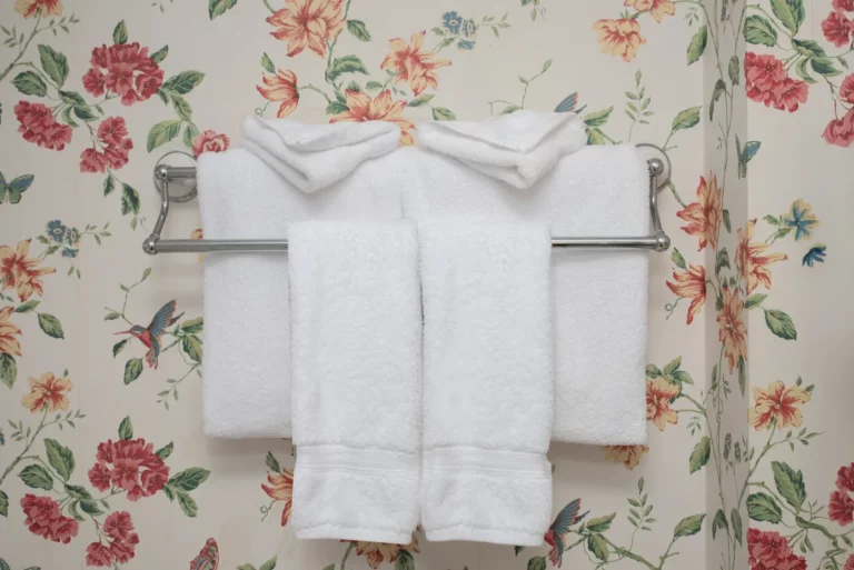 white folded towels against floral wallpaper.