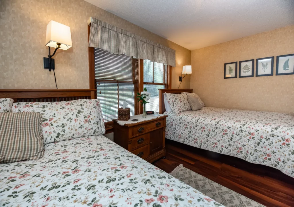 Twin beds with floral bedding in a warm bedroom.