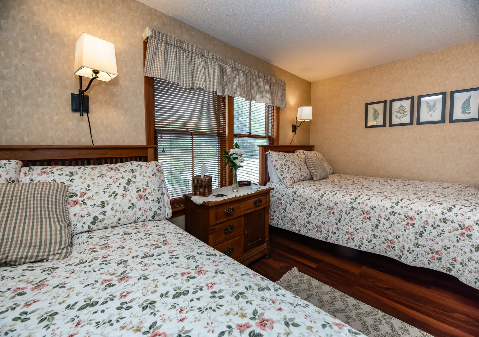 Twin beds with floral bedding in a warm bedroom.