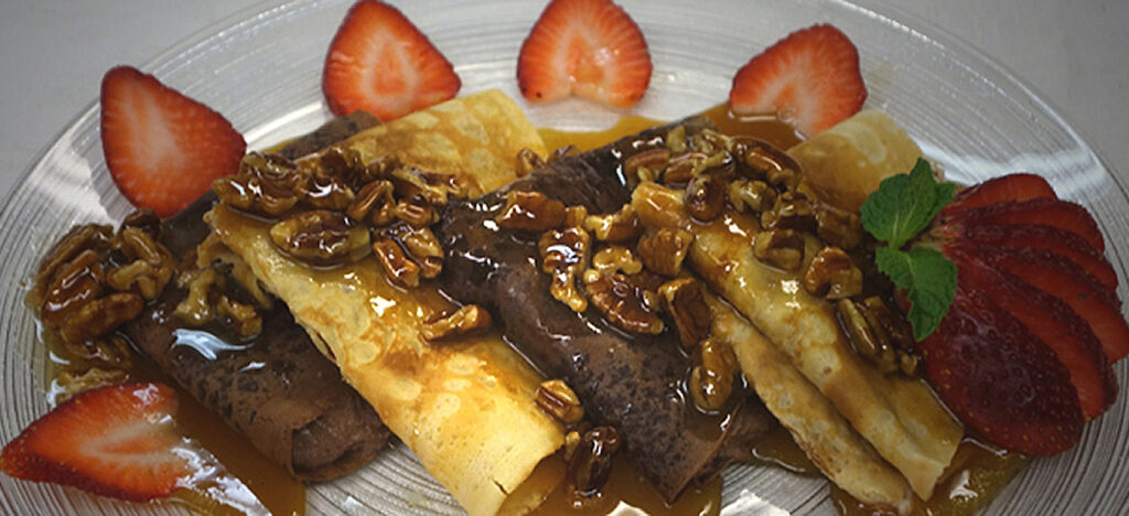 Chocolate & vanilla crepes with caramel pecan sauce & strawberry slices.