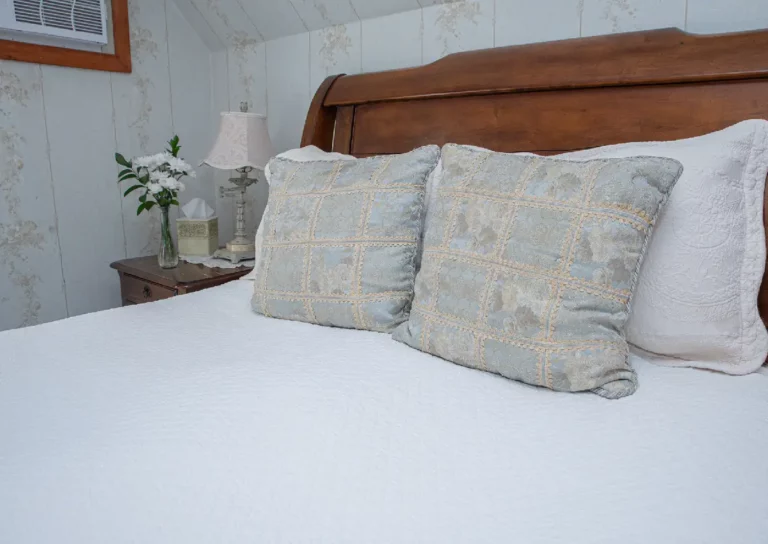 Bed with a wooden headboard, white pillows, and decorative accent pillows.